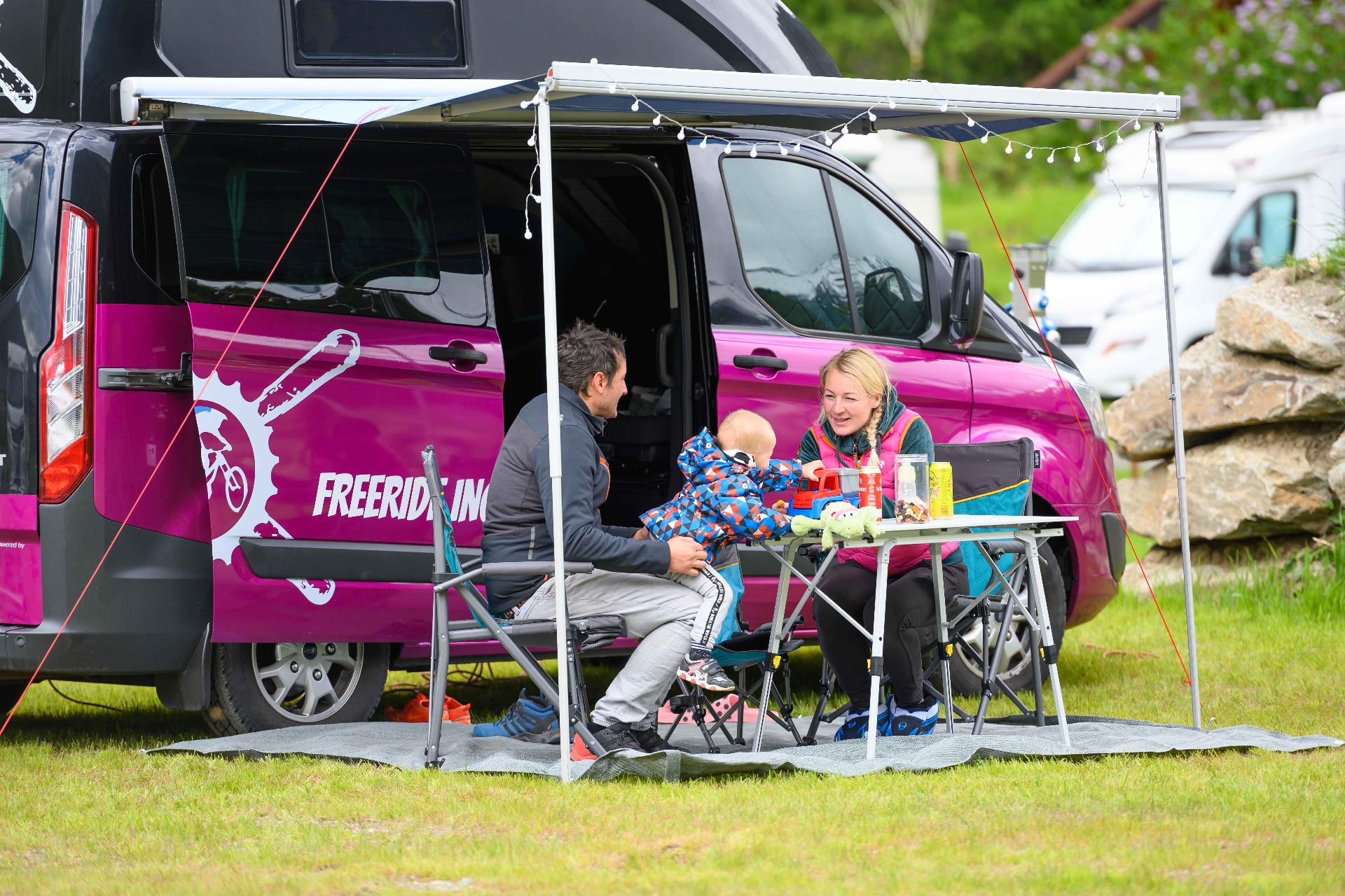 Familie beim Camping mit Wohnmobil auf HOCHoben